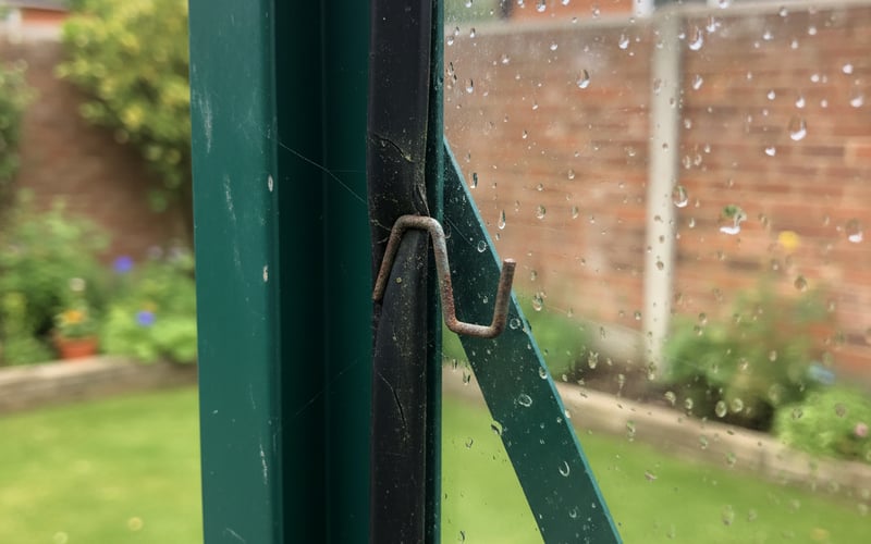 Close-up of rubber glazing seal and W-clip holding glass in an aluminium greenhouse frame