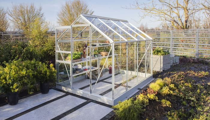 Glass greenhouse in a UK garden compared to polytunnel