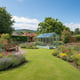 Lichfield 6x10 Wooden Greenhouse in wider garden landscape