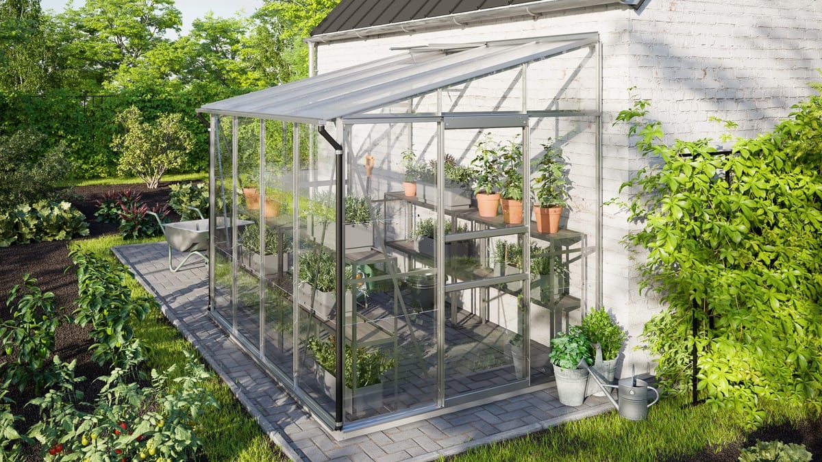 Vitavia IDA 5200 silver aluminium 6x8 lean-to greenhouse fitted against a UK brick house wall, single sloping mono-pitch roof shedding to the front — example of a wall-mounted lean-to greenhouse installation